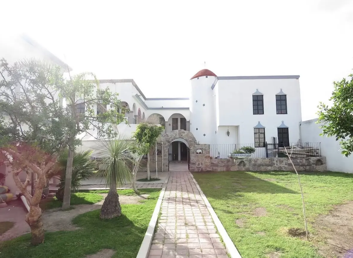 Fachada del Instituto Rabindranath Tagore: edificio blanco con arcos, torre y jardín con andador de ladrillo