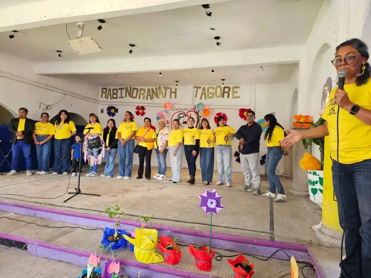 Equipo docente del instituto en el escenario durante una ceremonia, con plantas entregadas a las familias
