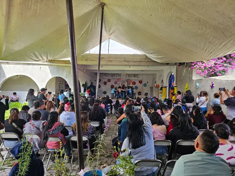 Festival escolar con el patio lleno de familias viendo a los niños bailar en el escenario